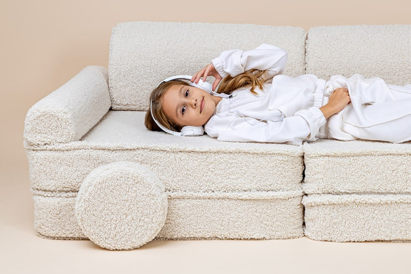 Child resting on a cream bouclé play sofa